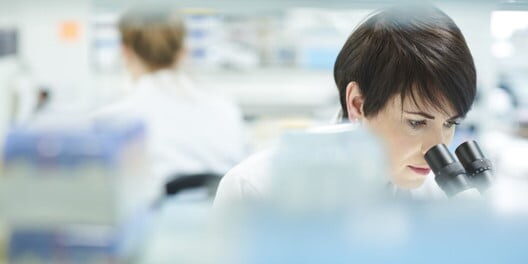 healthcare lab technician using microscope